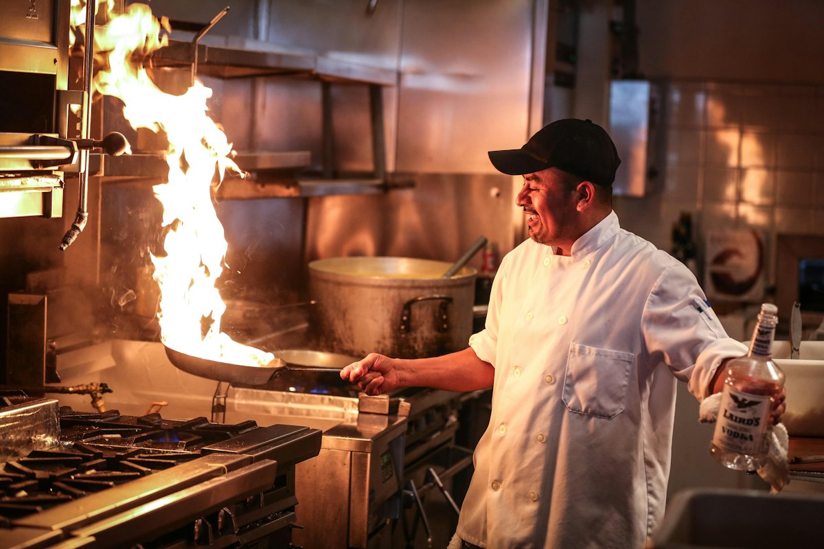 A cook tempering spices over a high flame